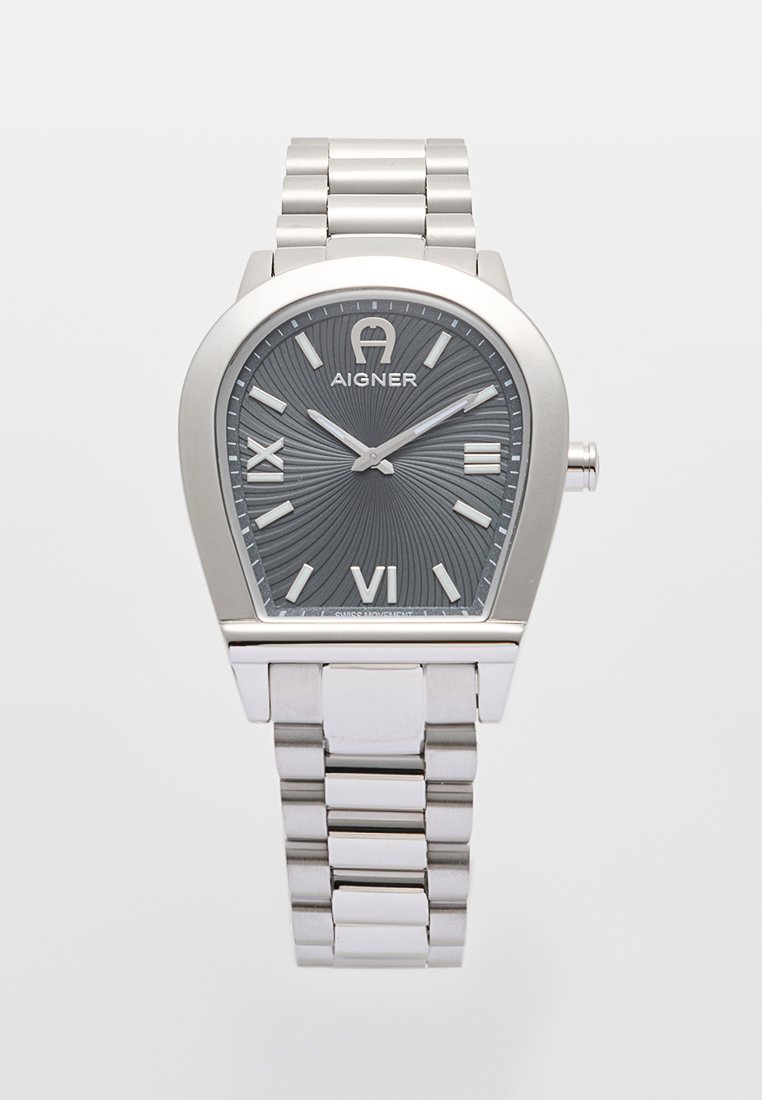 Silberne Edelstahl-Uhr mit einem grauen strukturierten Zifferblatt. Römische Ziffern VI, IX und ein Aigner-Logo oben. Gebogene Gehäuseform.