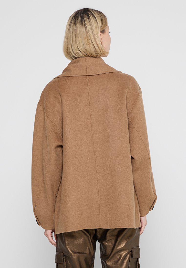 Brauner Wollmischungs-Mantel mit breitem Kragen und oversized Schnitt. Verfügt über fallende Schultern und geknöpfte Manschetten. Glatte Textur mit minimaler Detailierung.