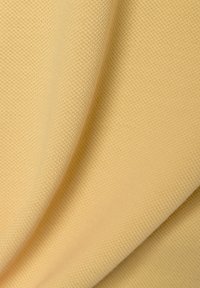 Helles gelbes Textil mit einer strukturierten Oberfläche und gewebtem Muster, das eine glatte Oberfläche und sanfte Drapierung zeigt.