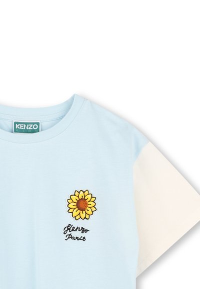 T-shirt di cotone azzurra con maniche corte; presenta una grafica di un girasole e "Kenzo Paris" ricamato in nero sotto il design.