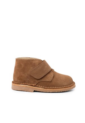 Chaussure bébé en suède marron avec une large bande velcro et une semelle en caoutchouc cousue, montrée de profil sur fond blanc.