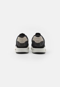 Schwarze Sneakers mit einer strukturierten Oberseite, Suede-Akzenten und weißen Mittelsohlen. Verfügt über ein sichtbares Logo und einen gepolsterten Kragen für zusätzlichen Komfort.