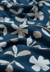 Granatowy materiał w kwiatowy wzór z beżowymi kwiatami i liśćmi, o miękkiej teksturze i lekko pogniecionej powierzchni.
