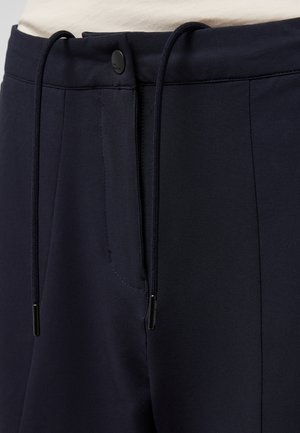 Marineblauwe broek met koordsluiting, voorzien van een gladde textuur en zijzakken. Inclusief een zwarte knopendetail op de tailleband.
