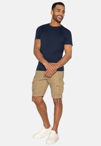 Marineblå kortærmet T-shirt med rund hals, parret med khaki cargo-shorts med sidelommer og hvide sneakers.