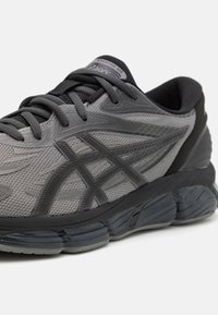 Gray running shoe with a breathable mesh upper, textured patterns, and a cushioned sole. Features a black rubber outsole and gray laces.