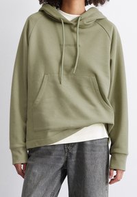 Olivgrön huvtröja med ficka fram, dragsko i huvan och ribbade ärmslut. Har en subtil präglad logotyp över bröstet.