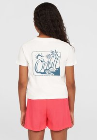 Hvid t-shirt med blå grafik, der viser en sol, palmetræer og designet "O'Neill Surf Supply Co.", parret med pink shorts.