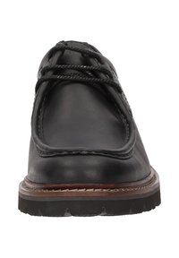 Scarpa in pelle nera con punta arrotondata, cuciture a rilievo e suola spessa in gomma. Presenta un design con lacci e un accento sulla parte centrale della suola ben visibile.