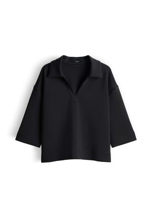 Pull noir raccourci avec un col à revers, des manches larges et une coupe décontractée. Fabriqué à partir d'un matériau doux et lisse avec des coutures minimales.