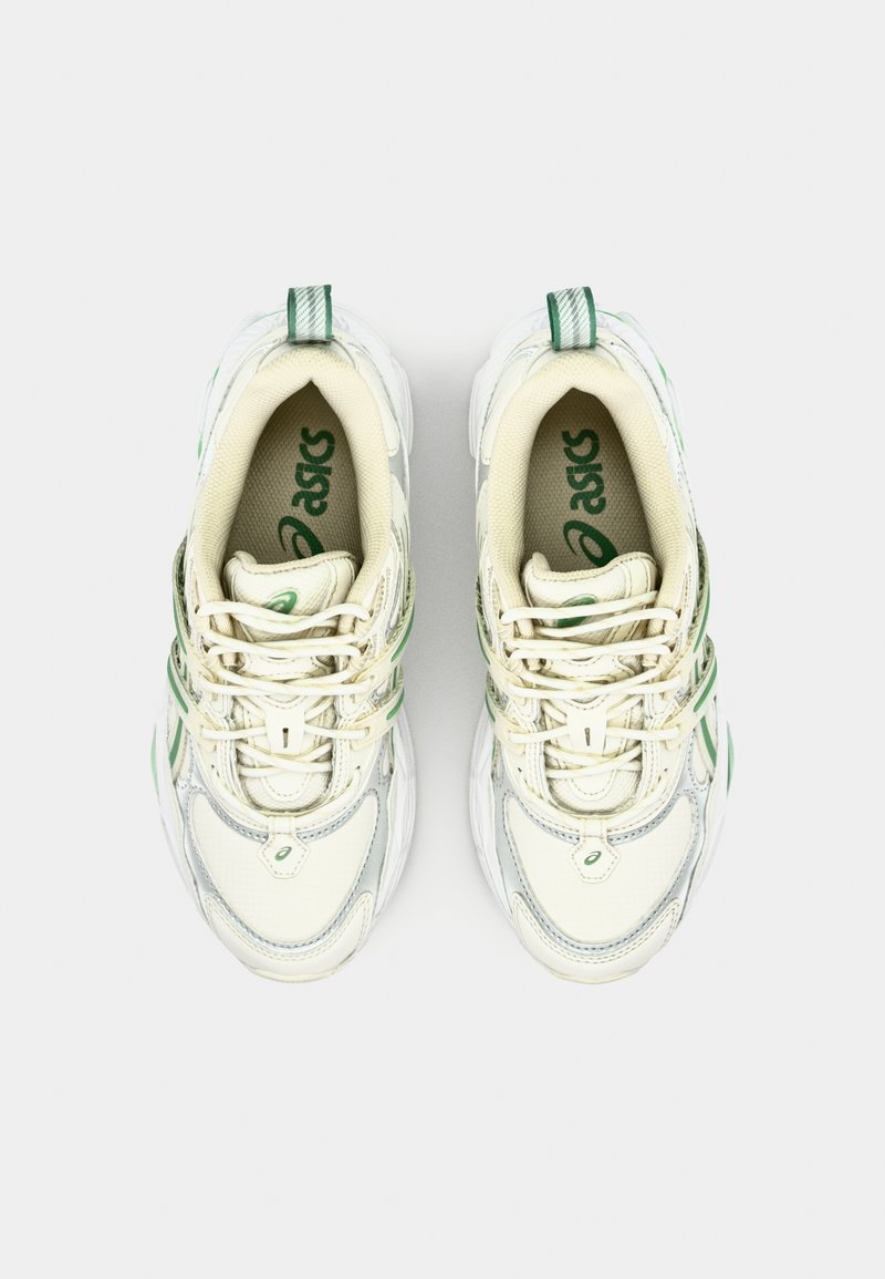 Baskets blanches avec accents verts, en matériaux en mesh et synthétiques, à bout rond, avec un collier rembourré et un design à lacets.