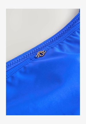 Tessuto blu brillante con una texture liscia, caratterizzato da un bordo cucito e un dettaglio del logo in tono oro. Adatto per costumi da bagno o abbigliamento sportivo.