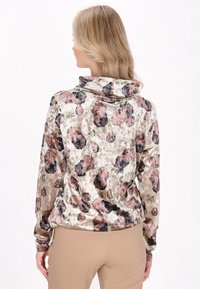 Fløjlsbluse med cowl-neck og blomstermønster i pink, sort og beige. Lange ærmer og rynket kantdetalje. Blød tekstur.