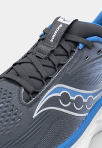Baskets de sport grises avec tige en maille, accents bleus et logo. Présente une surface texturée, une forme arrondie et un design de fermeture à lacets classique.