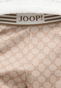 Tissu beige à motifs avec des formes hexagonales et de petits motifs floraux, doté d'une ceinture élastique marron avec le logo "JOOP!" et des rayures.