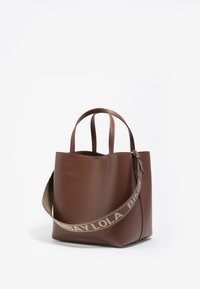 Bolso tote de piel marrón con dos asas cortas y una correa para el hombro desmontable. Diseño minimalista con una textura suave y sin hardware visible.