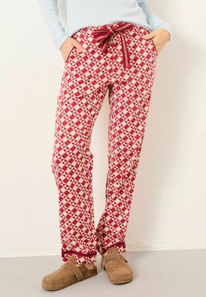 Rote und weiße geometrisch gemusterte Hose mit maroonem Zugband, kombiniert mit beigen Slipper aus Wildleder und einem hellblauen Langarmoberteil.
