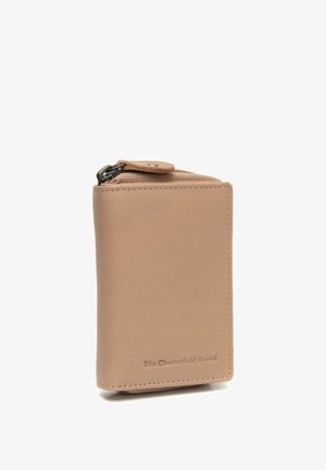Cartera compacta de piel beige con bordes cosidos, bolsillo con cremallera para monedas y "The Chesterfield Brand" grabado en la esquina inferior derecha del frente.