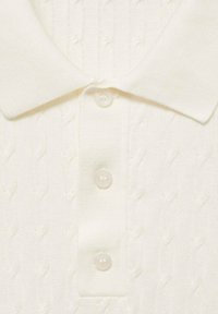 White knitted polo shirt featuring a ribbed collar, five buttons, and a textured pattern with subtle indentations throughout the fabric.