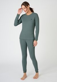 Conjunto de camiseta térmica verde y leggings, confeccionado en una tela suave, con mangas largas, puños acanalados y detalles de costura a lo largo de las piernas.
