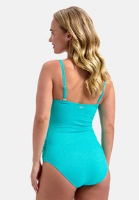 Bañador de una pieza en color turquesa, con tirantes finos, tejido texturizado y un diseño ajustado. Incluye un detalle de hardware dorado en la parte posterior.