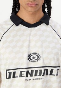 White checkered short-sleeve jersey with a black collar. Features a circular logo and bold black text reading "GLENDALE 91224 LA COUNTY."