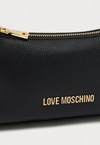 Μαύρο καλλυντικό τσαντάκι από δερματίνη με υφή, με χρυστό φερμουάρ και ανάγλυφη επιγραφή «LOVE MOSCHINO» σε χρυσά γράμματα στο μπροστινό μέρος.