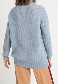 Ljusblå stickad tröja med långa ärmar, med en lös passform, ribbat mönster och design med sänkt axel.