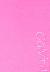 Pink cotton fabric with a ribbed texture, featuring an embossed "Calvin Klein" logo along the side, creating a subtle contrast.