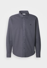 Dunkelgraues, langärmliges Hemd zum Knöpfen mit geknöpftem Kragen und kleinem, auf der linken Brust eingesticktem "cK"-Logo.