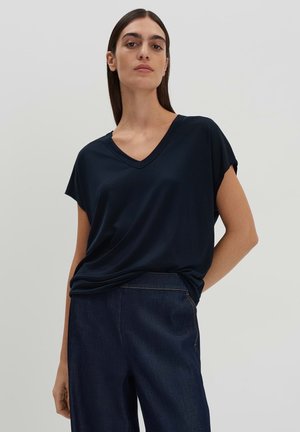 Navy V-neck t-shirt with short sleeves, made of soft fabric. Features a relaxed fit and drapes slightly at the waist. Paired with dark denim.