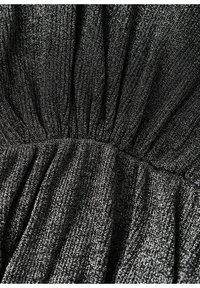 Gros plan d’un tissu noir avec des fils métalliques argentés, froncé et plissé pour créer de la texture et de la brillance.