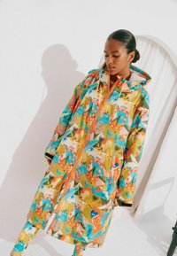 Kleurjack met capuchon, waterdicht, met een levendig patroon van bloemen en geometrische vormen in tinten van geel, blauw en oranje.