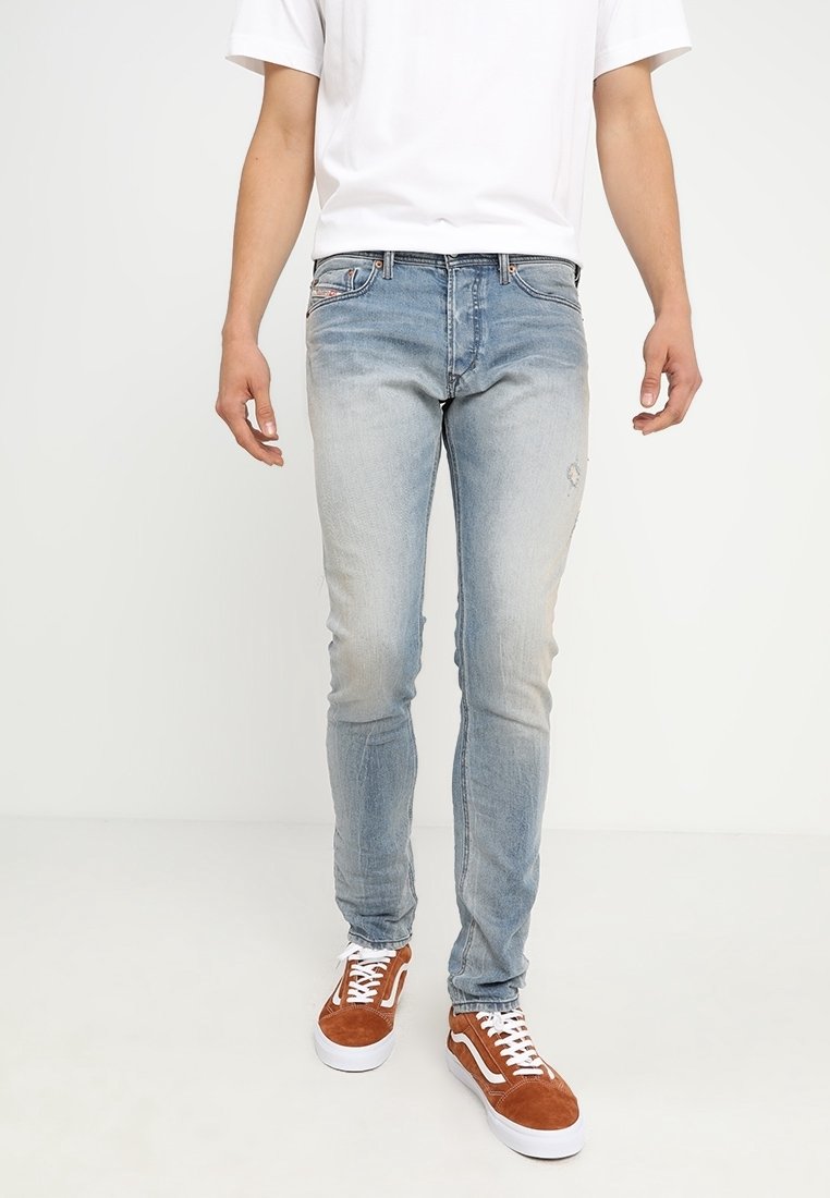 Ljusblå denimjeans med slim fit, som har en blekt finish och subtila slitningar. I kombination med oranga-bruna mockaskor.