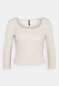 Ljusbeige ribbad långärmad topp med rundad halsringning och figurnära passform. Det mjuka tyget och den subtila texturen förstärker den enkla designen.