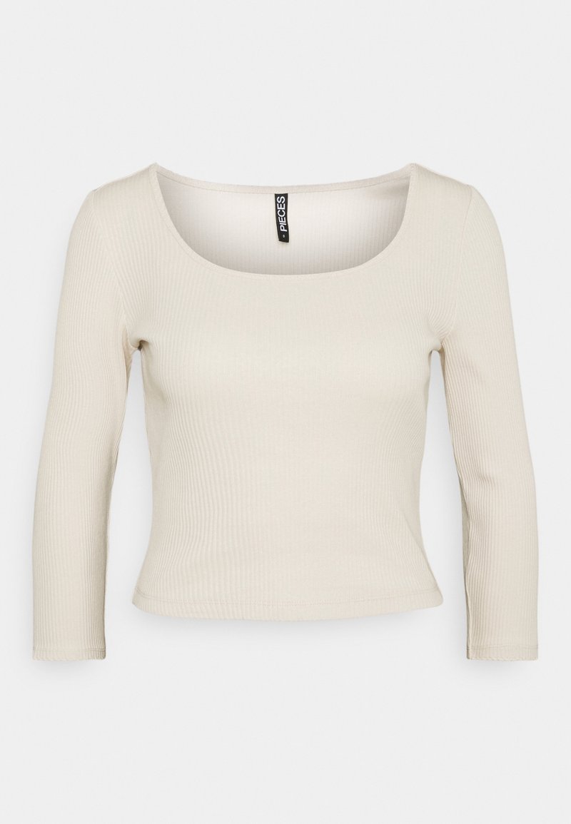 Ljusbeige ribbad långärmad topp med rundad halsringning och figurnära passform. Det mjuka tyget och den subtila texturen förstärker den enkla designen.
