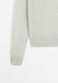 Light grey knitted sweater sleeve and lower torso section with ribbed cuffs and hem on a white background.