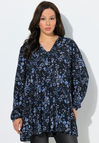 Blouse fleurie bleu marine avec des fleurs bleues et violettes, manches longues et encolure en V. Tissu léger avec une coupe ample et des plis subtils.