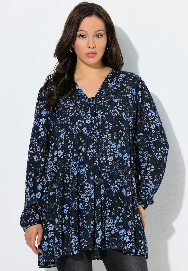 Blouse fleurie bleu marine avec des fleurs bleues et violettes, manches longues et encolure en V. Tissu léger avec une coupe ample et des plis subtils.