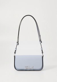Světle modrá kabelka přes rameno s elegantním designem, černým lemováním, nastavitelným popruhem a stříbrným logem na přední straně. Hladká textura.