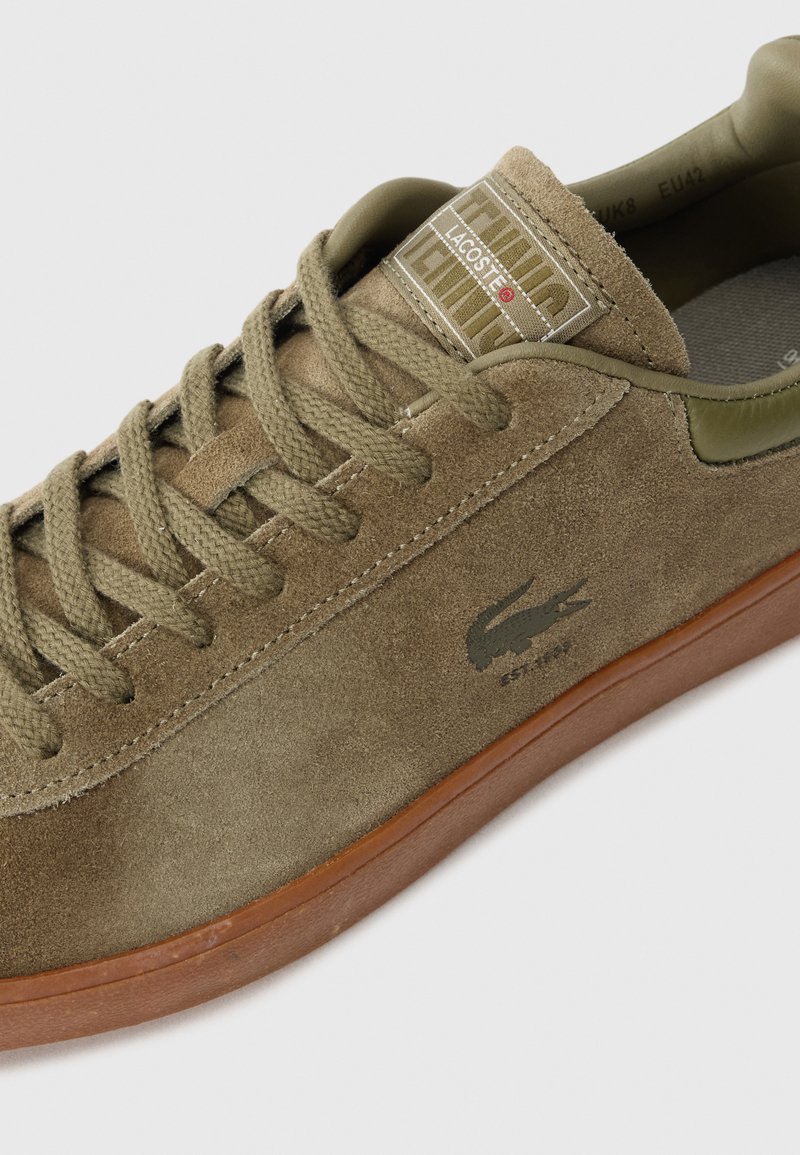 Sneakers en suède marron Lacoste avec des lacets assortis, semelle en caoutchouc, et logo crocodile sur le côté, taille EU 42.