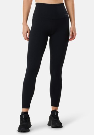 Black high-waisted leggings made of stretchy material, featuring a smooth texture and a form-fitting design, paired with black athletic shoes.