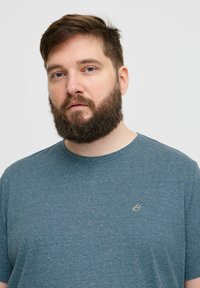 Kék, heatheres pamut póló kerek nyakkivágással és rövid ujjakkal, mellkason egy kis arany logóval.