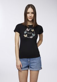 T-shirt nera a maniche corte con una grafica colorata di una farfalla e il testo "Innamorati ogni giorno" in un design circolare.