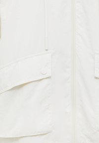 Biała lekka kurtka o gładkiej fakturze, zapinana na zamek z przodu, z dwoma dużymi kieszeniami z klapami, z minimalnymi detalami metalowymi.