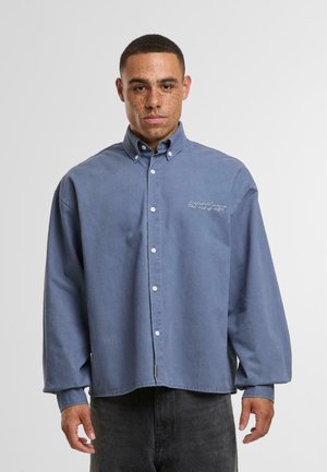 Camicia button-up in cotone blu con vestibilità rilassata, dotata di colletto, maniche lunghe e un discreto logo ricamato sul petto.