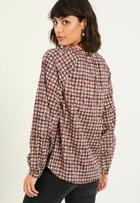 Floral patterned blouse in soft fabric, featuring a round neckline, long sleeves, and pleated back detail. Colors include pink, blue, and navy.