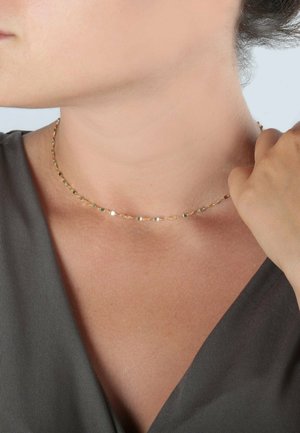 Goldener Choker-Halsreif mit einer zarten Kette, die aus kleinen, flachen, geometrischen Gliedern besteht. Glatte Oberfläche mit glänzendem Finish.