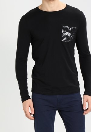 Černé tričko s dlouhým rukávem z bavlny, s kulatým výstřihem a kontrastní kapsou s mramorovým vzorem na levé straně hrudi.