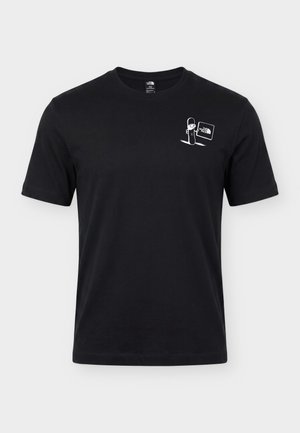 Hombre que lleva una camiseta negra con un gráfico blanco de telesilla, montañas, esquís y bastones con el texto "Opposites Attract" en la espalda.